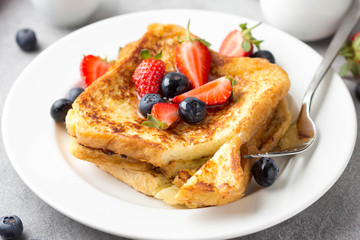 Wall Mural - French toast with berries (blueberries, strawberries) and sauce, traditional sweet dessert of bread with egg and milk. Morning baking food