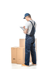 Wall Mural - back view of mover in uniform writing in clipboard near cardboard boxes isolated on white