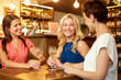 © Syda Productions - people, celebration and lifestyle concept - happy women drinking wine and talking at bar or restaurant