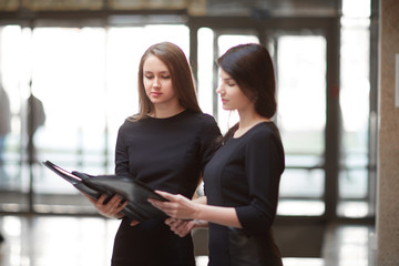 Wall Mural - two business women read business documents standing in the office lobby.