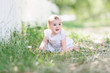 © laniko - baby girl wearing white dress sitting on the grass