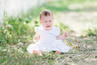 © laniko - baby girl wearing white dress sitting on the grass