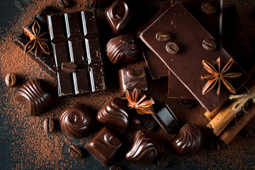 Assortment of dark, white and milk chocolate stack, chips. Chocolate and coffee beans on rustic wooden sacking background. Spices, cinnamon. Selective macro focus. Chocolates background. Sweets