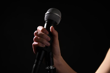 Wall Mural - Woman holding microphone on black background, closeup