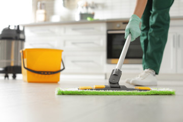 Wall Mural - Professional janitor cleaning floor with mop in kitchen, closeup