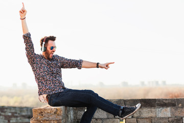 Young man enjoying listening to the music on headphones in sunset