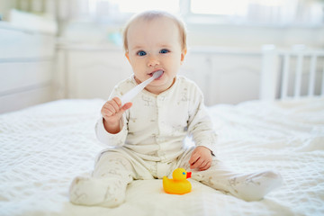 Wall Mural - Cute little girl with toothbrush in pyjamas on bed