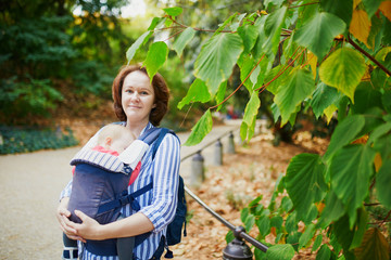 Wall Mural - Happy young woman with her baby in carrier