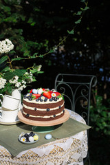 Poster - Chocolate layered  Easter cake decorated with easter eggs, berries and flowers, In the garden.