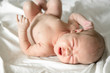 © kapichka - Newborn naked baby crying on the bed