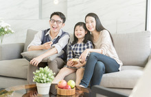 Happy Asian Family Watching Tv Together On Sofa In Living Room. Family And Home Concept