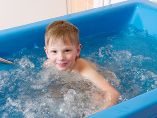 Wall Mural - baby boy is taking a bath with bubbles. Jacuzzi bubble bath procedure.