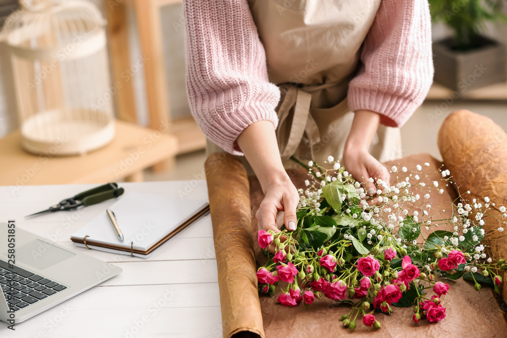 Beautiful female florist working at table in shop, closeup