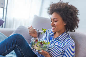 Wall Mural - Beautiful woman on the sofa eating a healthy salad.