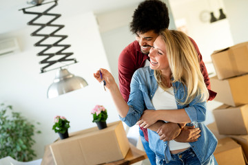 Wall Mural - Young happy couple moving in new home and unpacking boxes