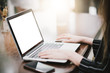 © Thaspol - Mockup image of a businesswoman using laptop with blank white desktop screen with coffee cup on wooden table in cafe