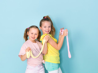 two beautiful girls playing with homemade slime and having a lot of fun in front of blue background