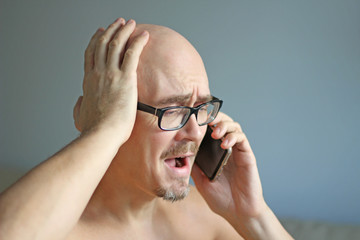 Young handsome man in black glasses is talking on the phone. Big problems, scandal, bad news. Closeup portrait of a man. Manager, office worker talking on the phone. Copy space for your text