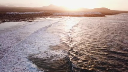 Wall Mural - Ocean beach with rolling waves at sunset, aerial video from drone of Atlantic coast on Canary islands, scenic landscape, popular surfing spot