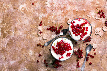 Wall Mural - Healthy dessert with organic red currants, fresh yogurt and corn flakes. Dietary breakfast on a brown background