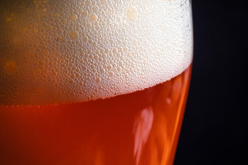 Four glasses with red beer on a dark background.