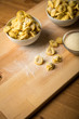 Frische, rohe Cappelletti Tortellini Pasta mit Mehl und Grieß in Porzellan Schale auf Holz Brett