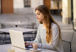 © SB Arts Media - Attractive young woman studying or working in a coffee shop outside with laptop in european city