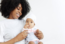 Closeup Portrait Of Beautiful African Woman Holding On Hands Her Little Daughter On White Background. Family, Love, Lifestyle, Motherhood And Tender Moments Concepts. Mother's Day Concept Or
