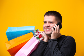 Brunet man with phone and multi-colored shopping bags