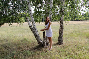 Young girl in a field near a birch tree