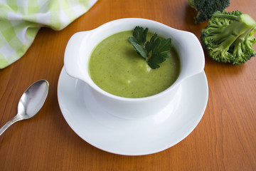 Wall Mural - Vegetarian  broccoli puree soup in th white bowl on the light  brown  wooden background