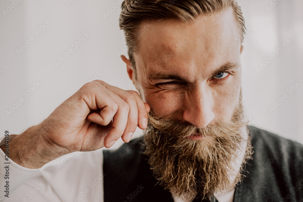 Handsome bearded hipster playing with his mustaches - obrazy, fototapety, plakaty 
