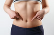 © mikhail_b_azarov - slender beautiful waist of a young woman close-up. on white background. She points two fingers at the bottom of her stomach.