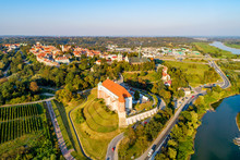 Sandomierz, Poland. Medieval Gothic Castle In Front, Old Town With Town Hall Tower,  Gothic Cathedral And Vistula River In The Background. Aerial View In Sunset Light