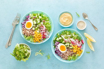 Wall Mural - Buddha bowl with boiled egg, rice and vegetable salad of fresh lettuce, radish, cucumber, corn, onion and sesame seeds and chickpea sauce