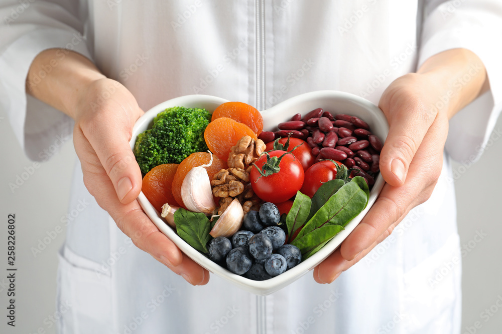 Doctor holding bowl with products for heart-healthy diet, closeup - obrazy, fototapety, plakaty 