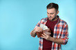 © New Africa - Happy young man putting money into wallet on color background. Space for text