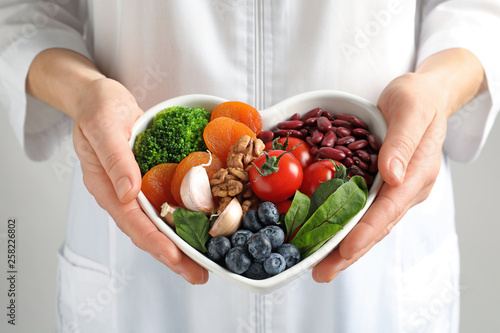 Doctor holding bowl with products for heart-healthy diet, closeup Tableau sur Toile