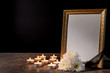 Blank funeral frame, candles and flowers on table against black background