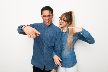 Wall Mural - Young couple with glasses frustrated by a bad situation and pointing to the front