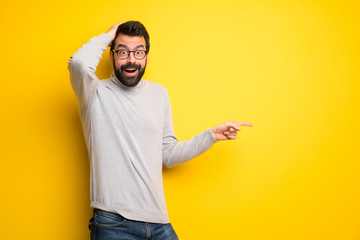 Wall Mural - Man with beard and turtleneck pointing finger to the side and presenting a product