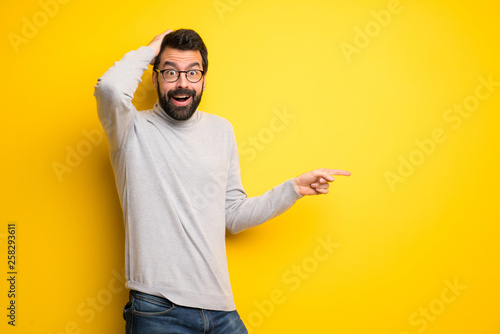 Fotografía Man with beard and turtleneck pointing finger to the side and presenting a produ
