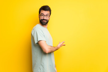 Man with beard and green shirt pointing back and presenting a product