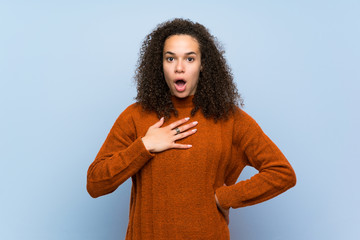 Dominican woman with curly hair surprised and shocked while looking right