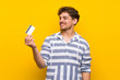 © luismolinero - Blonde man over yellow wall holding a credit card and thinking