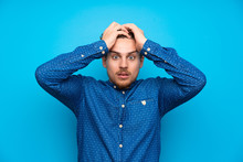 Blonde Man Over Isolated Blue Wall With Surprise Facial Expression