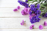 Fototapeta Lawenda - Fresh spring purple flower Marguerite and statice flowers frame composition plant on white wooden background