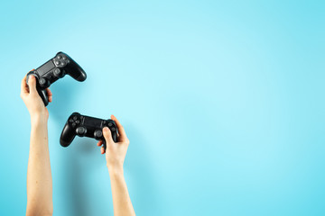 Two black joystick in hands isolated on pastel blue background