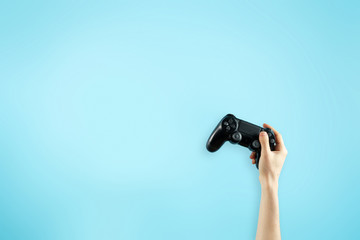 Black joystick in hands isolated on bright blue backg