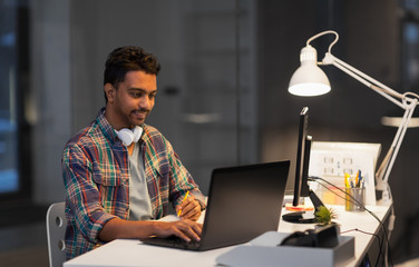 Wall Mural - deadline, technology and people concept - creative man with laptop computer working at night office